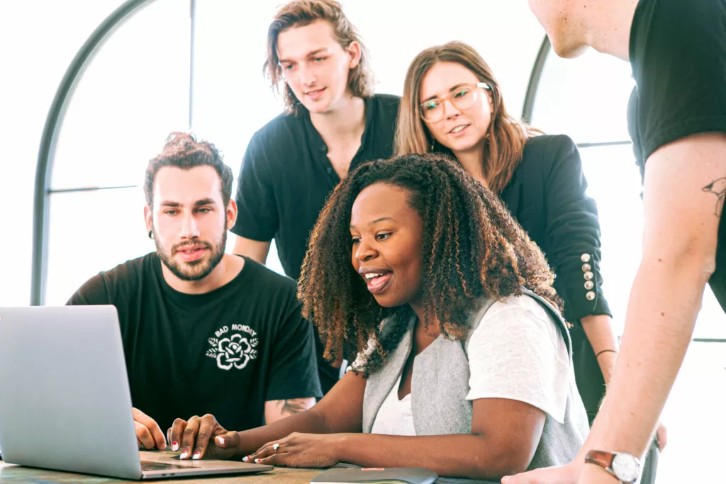 Group of young people looking at a laptop screen together