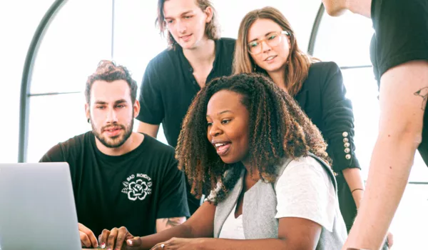 Group of young people looking at a laptop screen together