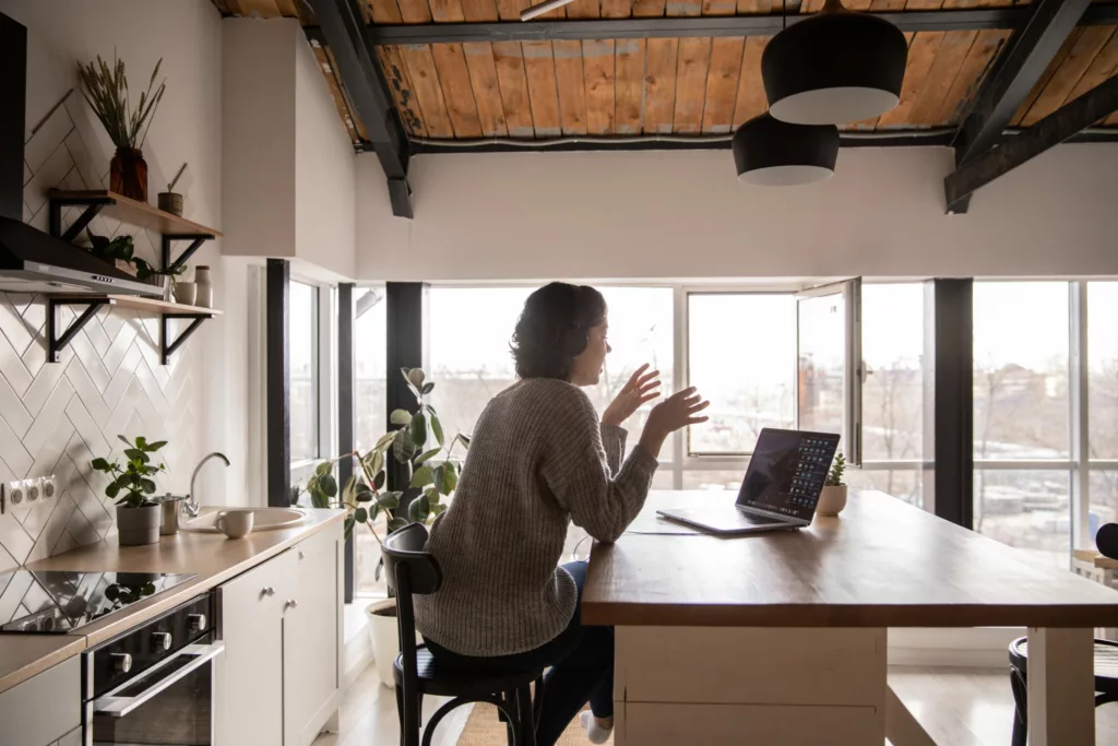 Woman sat in kitchen in a video meeting on her laptop