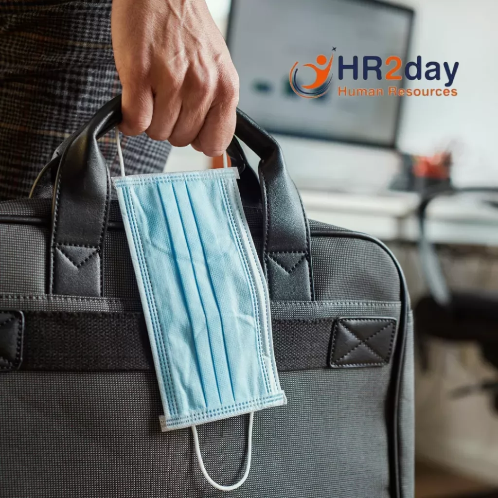 person in an office holding briefcase with disposable face mask